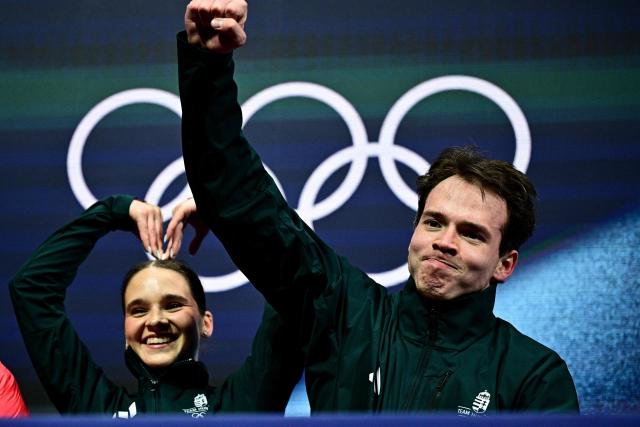 Hungary's Maria Pavlova and Hungary's Aleksei Sviatchenko react in the kiss and cry area after competing in the figure skating pair skating short program during the Milano Cortina 2026 Winter Olympic Games at Milano Ice Skating Arena in Milan on February 15, 2026. (Photo by JULIEN DE ROSA / AFP)