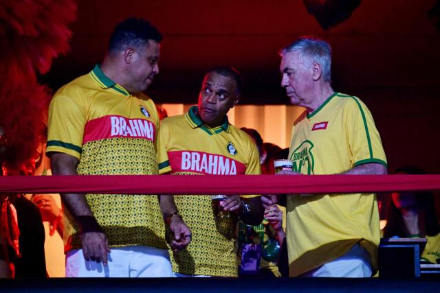 Brazil's Italian national football team coach Carlo Ancelotti (R) chats with former football players Ronaldo (L) and Denilson above a float of the Academicos de Niteroi samba school before the opening night of the Rio Carnival at the Marques de Sapucai Sambadrome in Rio de Janeiro, Brazil, on February 15, 2026. (Photo by Pablo PORCIUNCULA / AFP)