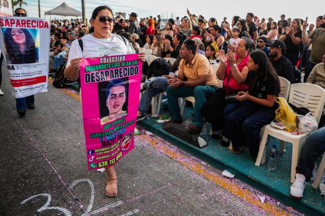 A member of a group of "searching mothers" holds a portrait of a missing person during the parade of International Carnival in Mazatlan, Sinaloa State, Mexico, on February 15, 2026. (Photo by Jesus Verdugo / AFP)