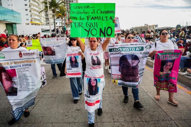A member of a group of "searching mothers" holds a banner that reads in Spanish "Estrella... you enjoy carnival with your family; why can't I?," during the parade of International Carnival in Mazatlan, Sinaloa State, Mexico, on February 15, 2026. (Photo by Jesus Verdugo / AFP)