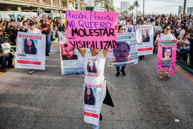 A member of a group of "searching mothers" holds a banner that reads in Spanish "Excuse me, excuse me, I don't want to bother you, just make you aware," during the parade of International Carnival in Mazatlan, Sinaloa State, Mexico, on February 15, 2026. (Photo by Jesus Verdugo / AFP)
