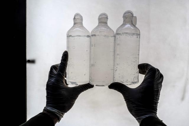 This photograph taken on February 3, 2026 shows an Afghan worker inspecting serum bottles inside a laboratory at the Milli Shifa Pharmaceutical (MSP) factory on the outskirts of Kabul. Afghanistan already produces a variety of serums including antibiotics, according to manufacturer Milli Shifa Pharmaceutical. The company makes 100,000 bottles daily and "can double the capability" if demand merits, CEO Nasar Ahmad Taraki told AFP. (Photo by Wakil KOHSAR / AFP)