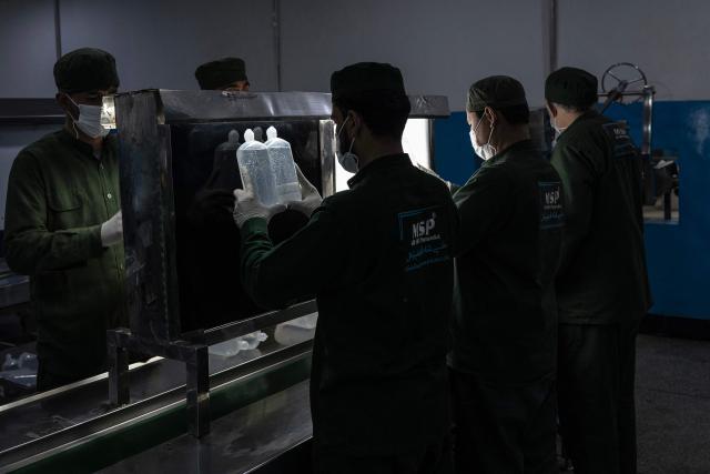 This photograph taken on February 3, 2026 shows Afghan workers inspecting serum bottles inside a laboratory at the Milli Shifa Pharmaceutical (MSP) factory on the outskirts of Kabul. Afghanistan already produces a variety of serums including antibiotics, according to manufacturer Milli Shifa Pharmaceutical. The company makes 100,000 bottles daily and "can double the capability" if demand merits, CEO Nasar Ahmad Taraki told AFP. (Photo by Wakil KOHSAR / AFP)