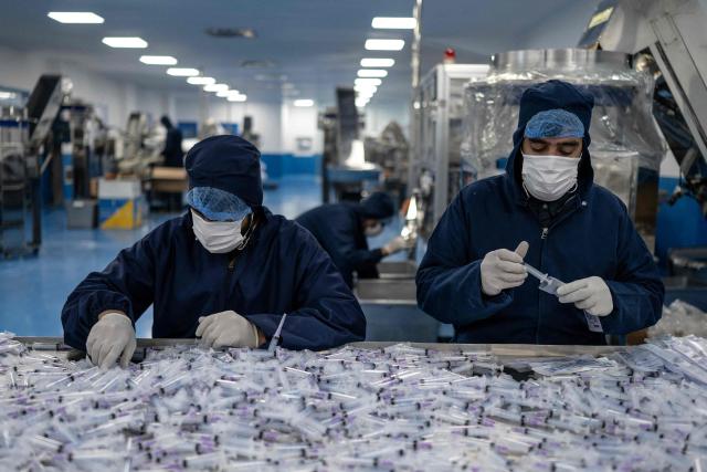 This photograph taken on February 3, 2026 shows Afghan workers assembling and packing disposable syringes at the Milli Shifa Pharmaceutical (MSP) factory on the outskirts of Kabul. Afghanistan already produces a variety of serums including antibiotics, according to manufacturer Milli Shifa Pharmaceutical. The company makes 100,000 bottles daily and "can double the capability" if demand merits, CEO Nasar Ahmad Taraki told AFP. (Photo by Wakil KOHSAR / AFP)