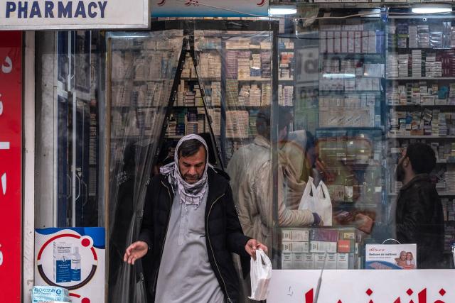 This photograph taken on February 9, 2026 shows an Afghan man carrying medicines walk out of a pharmacy in Kabul. Afghanistan's decision to overhaul its medicine market was meant to improve quality and boost domestic production, but industry specialists say the swift changes have led to a litany of problems. (Photo by Wakil KOHSAR / AFP)
