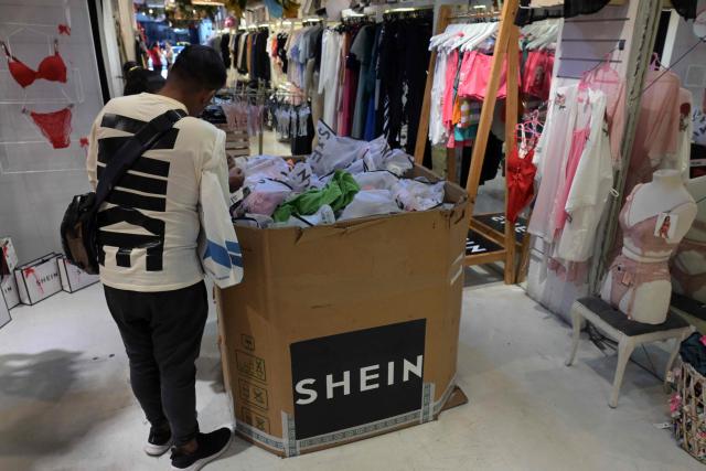 People look at imported clothes from Chinese brand Shein in a store in Buenos Aires on February 6, 2026. The textile industry in Argentina is going through a crisis with falling sales, rising local production costs, and concerns about competition from imports. Since 2023, the textile sector has laid off more than 18,000 people and is operating at one-third of its installed capacity, according to February data from the consulting firm Analytica and the Argentine Textile Industries Federation (FITA). (Photo by JUAN MABROMATA / AFP)