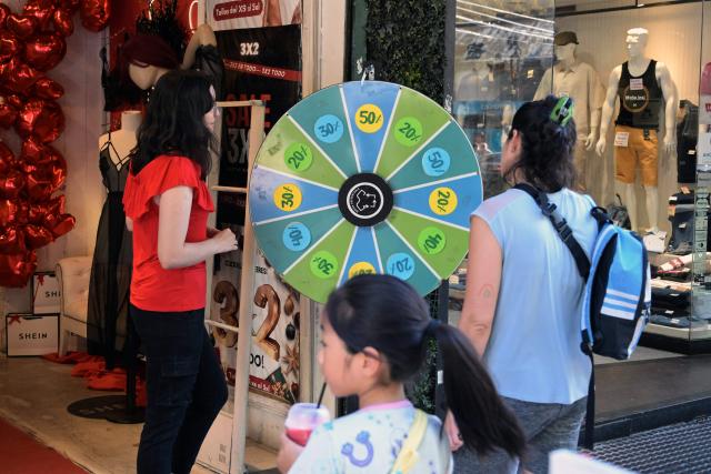 A roulette offering different discounts is used by customers at the entrance of a store that sells imported clothes from Chinese brand Shein in Buenos Aires on February 6, 2026. The textile industry in Argentina is going through a crisis with falling sales, rising local production costs, and concerns about competition from imports. Since 2023, the textile sector has laid off more than 18,000 people and is operating at one-third of its installed capacity, according to February data from the consulting firm Analytica and the Argentine Textile Industries Federation (FITA). (Photo by JUAN MABROMATA / AFP)