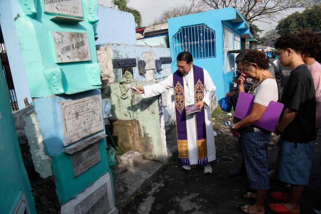 Roman Catholic priest Father Flavie Villanueva blesses the tomb of Edward Sentorias, a victim of former Philippine president Rodrigo Duterte's war on drugs, alongside relatives during an exhumation at a cemetery in Manila on February 16, 2026. The bones will be transferred to the University of the Philippines College of Medicine for examination. ICC prosecutors have charged Duterte with three counts of crimes against humanity, alleging his involvement in at least 76 murders between 2013 and 2018 as part of his "war on drugs". (Photo by Ted ALJIBE / AFP)
