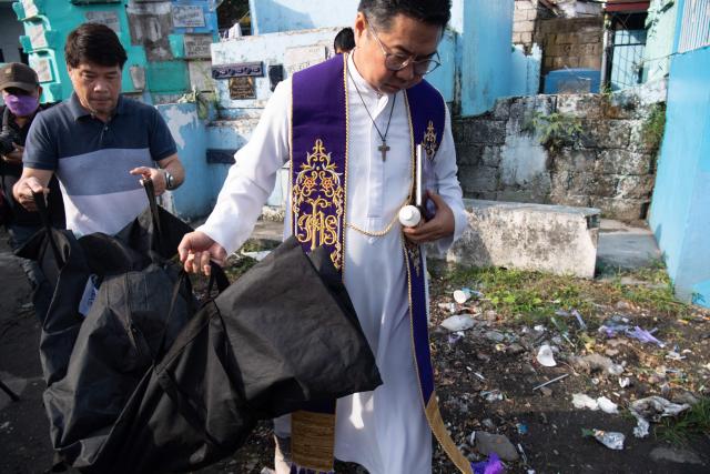 Roman Catholic priest Father Flavie Villanueva helps carry a body bag containing the remains of Edward Sentorias, a victim of former Philippine president Rodrigo Duterte's war on drugs, during an exhumation at a cemetery in Manila on February 16, 2026. The bones will be transferred to the University of the Philippines College of Medicine for examination. ICC prosecutors have charged Duterte with three counts of crimes against humanity, alleging his involvement in at least 76 murders between 2013 and 2018 as part of his "war on drugs". (Photo by Ted ALJIBE / AFP)