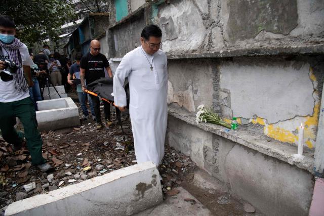 Roman Catholic priest Father Flavie Villanueva (R) helps carry a body bag containing the remains of Joewarski Pajo, a victim of former Philippine president Rodrigo Duterte's war on drugs, during an exhumation at a cemetery in Manila on February 16, 2026. The bones will be transferred to the University of the Philippines College of Medicine for examination. ICC prosecutors have charged Duterte with three counts of crimes against humanity, alleging his involvement in at least 76 murders between 2013 and 2018 as part of his "war on drugs". (Photo by Ted ALJIBE / AFP)