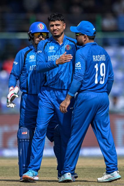 Afghanistan's Mujeeb Ur Rahman (C) celebrates with captain Rashid Khan (R) after taking the wicket of UAE's Alishan Sharafu during the 2026 ICC Men's T20 Cricket World Cup group stage match between Afghanistan and United Arab Emirates at the Arun Jaitley Stadium in New Delhi on February 16, 2026. (Photo by Arun SANKAR / AFP)