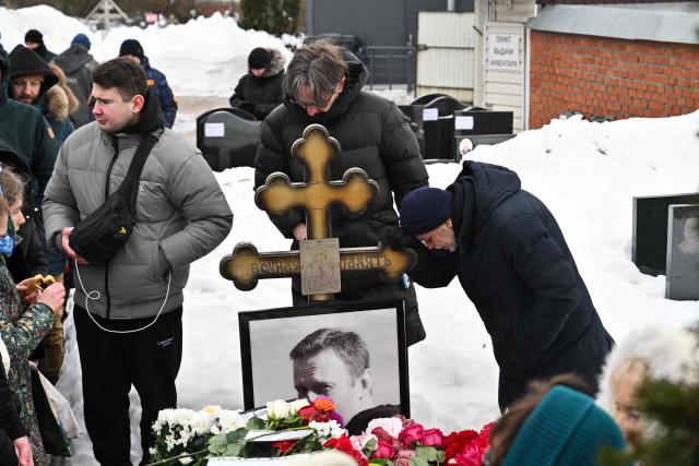 People visit the grave of Russian opposition leader Alexei Navalny at the Borisovo cemetery in Moscow on February 16, 2026, marking the second anniversary of his death in an Arctic colony. (Photo by Hector RETAMAL / AFP) / NAVALNY HAS BEEN DECLARED "EXTREMIST" BY RUSSIAN AUTHORITIES. IN RUSSIA, ANYBODY WHO MENTIONS NAVALNY OR HIS ANTI-CORRUPTION FOUNDATION WITHOUT STATING THAT THEY HAVE BEEN DECLARED "EXTREMIST" IS SUBJECT TO FINES OR UP TO FOUR YEARS IN PRISON FOR REPEATED OFFENCES. / 