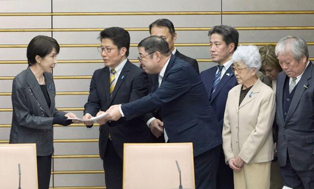 Japan's Prime Minister Sanae Takaichi (L) receives the campaign guidelines from Takuya Yokota (2nd L), head of the Association of Families of Victims Kidnapped by North Korea, and others at the Prime Minister's Office in Tokyo on February 16, 2026. (Photo by JIJI PRESS / AFP) / Japan OUT