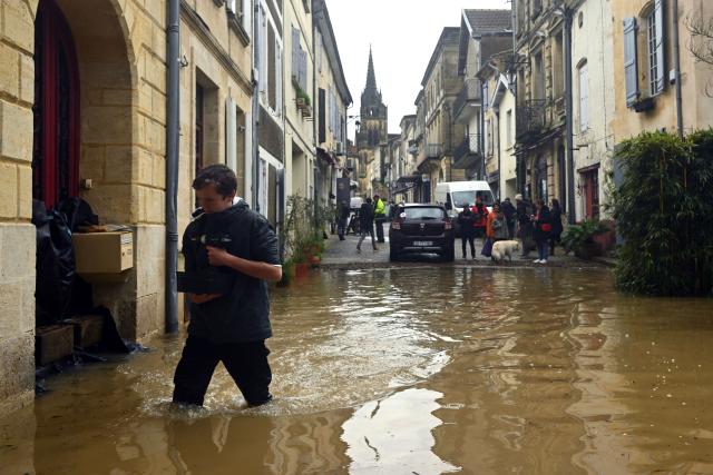 A local resident walks in a street flooded by the Garonne river in Cadillac-sur-Garonne, south-western France, on February 16, 2026. The flood alert system in France has been working at a record pace as relentless rain over the past month has saturated soils, the head of the agency told AFP on February 14, 2026. "For 30 days we have been in continuous orange or red alert somewhere on the national territory," Lucie Chadourne-Facon, director of Vigicrues, told AFP, referring to the two highest alert levels. (Photo by Gaizka IROZ / AFP)