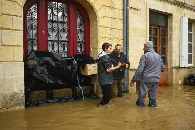 Local residents walk in a street flooded by the Garonne river in Cadillac-sur-Garonne, south-western France, on February 16, 2026. The flood alert system in France has been working at a record pace as relentless rain over the past month has saturated soils, the head of the agency told AFP on February 14, 2026. "For 30 days we have been in continuous orange or red alert somewhere on the national territory," Lucie Chadourne-Facon, director of Vigicrues, told AFP, referring to the two highest alert levels. (Photo by Gaizka IROZ / AFP)