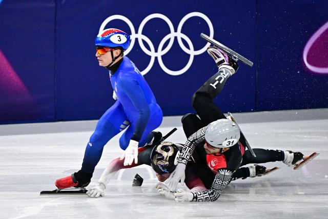 Italy's Pietro Sighel, Latvia's Reinis Berzins and Turkey's Furkan Akar crash during the short track speed skating men's 500m heats during the Milano Cortina 2026 Winter Olympic Games at Milano Ice Skating Arena in Milan on February 16, 2026. (Photo by JULIEN DE ROSA / AFP)