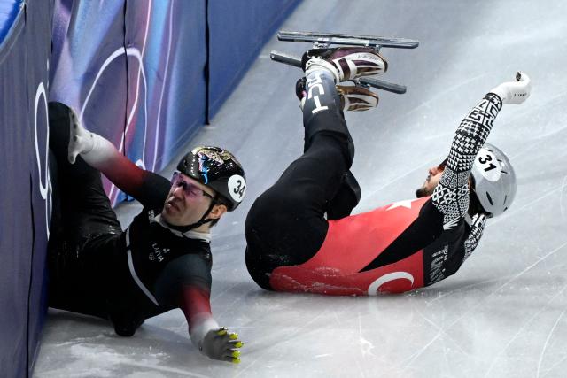 Latvia's Reinis Berzins and Turkey's Furkan Akar crash during the short track speed skating men's 500m heats during the Milano Cortina 2026 Winter Olympic Games at Milano Ice Skating Arena in Milan on February 16, 2026. (Photo by WANG Zhao / AFP)