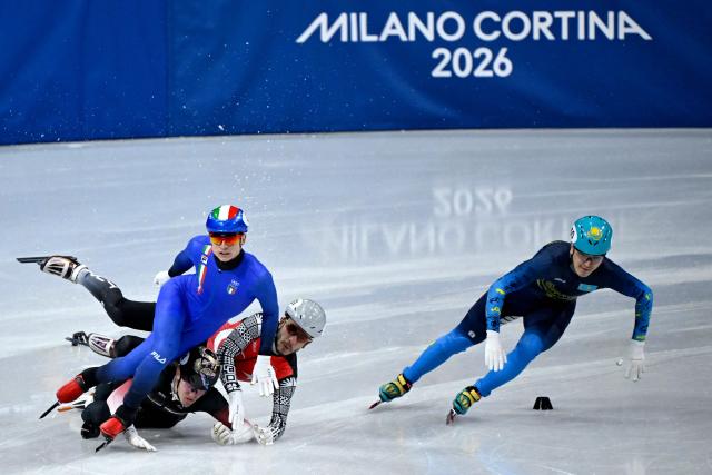 Italy's Pietro Sighel, Latvia's Reinis Berzins, Turkey's Furkan Akar crash as Kazakhstan's Abzal Azhgaliyev skates past them during the short track speed skating men's 500m heats during the Milano Cortina 2026 Winter Olympic Games at Milano Ice Skating Arena in Milan on February 16, 2026. (Photo by WANG Zhao / AFP)