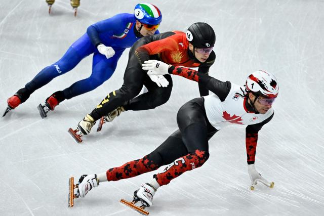 Canada's William Dandjinou, China's Liu Shaoang and Italy's Pietro Sighel compete in the short track speed skating men's 5000m relay semi-final during the Milano Cortina 2026 Winter Olympic Games at Milano Ice Skating Arena in Milan on February 16, 2026. (Photo by WANG Zhao / AFP)