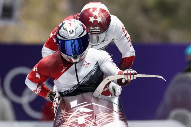 Latvia's Jekabs Kalenda and Latvia's Matiss Miknis compete in the bobsleigh men's 2-man heat 1 at Cortina Sliding Centre during the Milano Cortina 2026 Winter Olympic Games in Cortina d'Ampezzo on February 16, 2026. (Photo by FRANCK FIFE / AFP)
