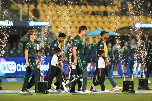 Sri Lanka's captain Dasun Shanaka (R) enters the pitch with his Australian counterpart Mitchell Marsh (3R) before the start of the 2026 ICC Men's T20 Cricket World Cup group stage match between Australia and Sri Lanka at Pallekele International Cricket Stadium in Kandy on February 16, 2026. (Photo by Ishara S. KODIKARA / AFP)