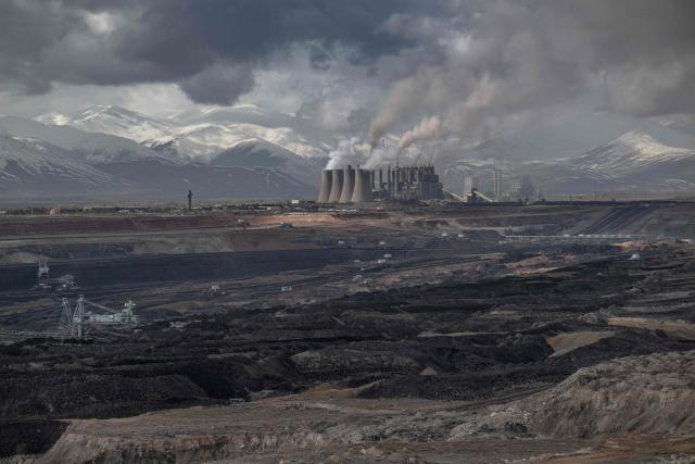 Mining vehicles extract coal from a lignite coal mine, as the Elbistan thermal power plant, is seen in the background in Elbistan on February 11, 2026. The power plant has operated since 1984 and is one of Turkey's largest thermal facilities, with eight units generating 2,795 megawatts. It relies on lignite from the Afsin?Elbistan basin, which holds around 40 percent of the country's known reserves. (Photo by Ozan KOSE / AFP)