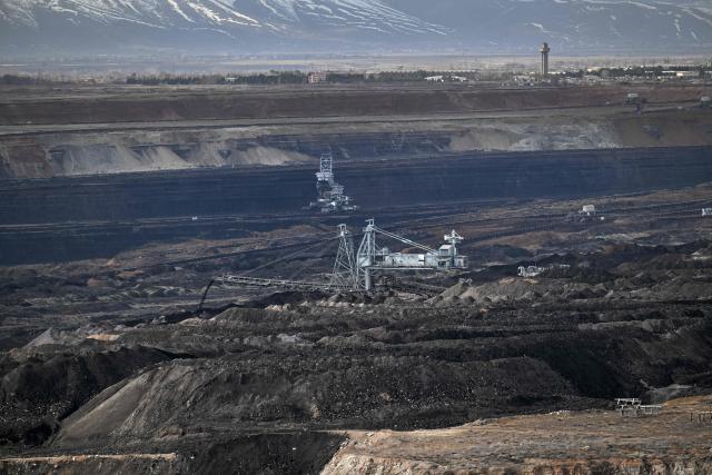 Mining vehicles extract coal from a lignite coal mine, as the Elbistan thermal power plant, is seen in the background in Elbistan on February 11, 2026. The power plant has operated since 1984 and is one of Turkey's largest thermal facilities, with eight units generating 2,795 megawatts. It relies on lignite from the Afsin?Elbistan basin, which holds around 40 percent of the country's known reserves. (Photo by Ozan KOSE / AFP)