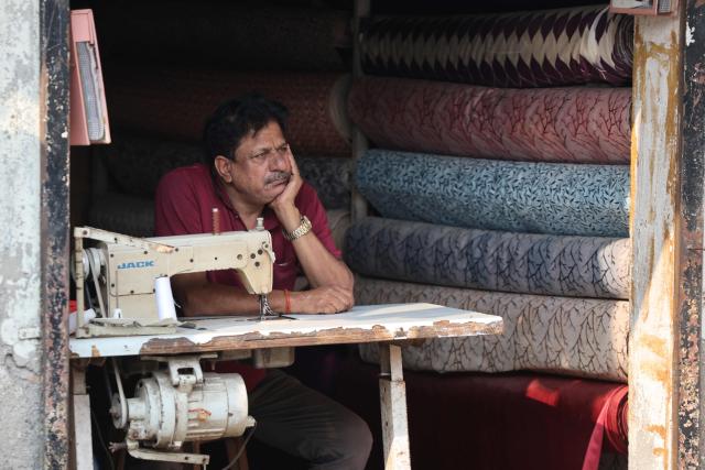 A tailor looks on as he waits for customers at his shop in Mumbai on February 16, 2026. (Photo by Ludovic MARIN / AFP)