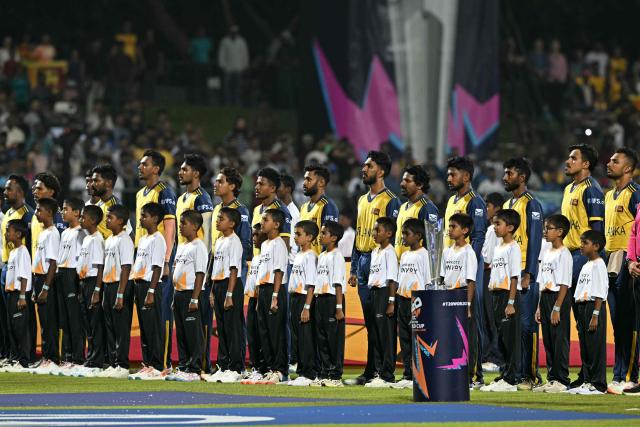 Sri Lanka's team players stand for the national anthem next to the 2026 ICC Men's T20 Cricket World Cup trophy before the start of the tournament group stage match between Australia and Sri Lanka at Pallekele International Cricket Stadium in Kandy on February 16, 2026. (Photo by Ishara S. KODIKARA / AFP)