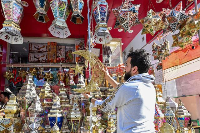 A vendor arranges decorations outside his shop at a market in Kuwait City on February 16, 2026, as Muslims prepare for the holy month of Ramadan. For Muslims across the world, the beginning of the ninth month in the Muslim lunar calendar which marks the start of Ramadan, is a time for spiritual reflection, prayers, fasting and family reunions around the table after breaking the fast. (Photo by YASSER AL-ZAYYAT / AFP)