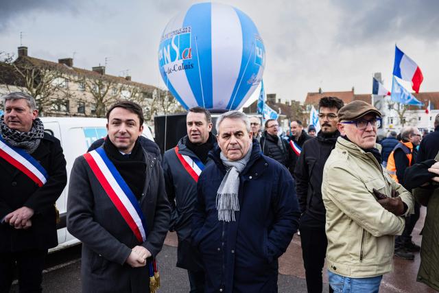 President of the center-right "Nous France" party, Xavier Bertrand (C), and Mayor of Arques Benoit Roussel (2ndL) take part in a rally on the eve of the formal submission of takeover offers for glassmaking giant Arc in Arques, northern France on February 16, 2026. Around 500 Arc employees and political figures demonstrated in Arques (Pas-de-Calais) on February 16, 2026, on the eve of the deadline for submitting takeover bids for the glassmaker, which was placed in receivership in early January. (Photo by Sameer Al-DOUMY / AFP)