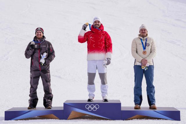 From (L-R) Austria's silver medalist Fabio Gstrein, Switzerland's gold medalist Loic Meillard, and Norway's bronze medalist Henrik Kristoffersen celebrate on the podium of the men's slalom alpine skiing event during the Milano Cortina 2026 Winter Olympic Games at the Stelvio Ski Centre in Bormio (Valtellina) on February 16, 2026. (Photo by Dimitar DILKOFF / AFP)