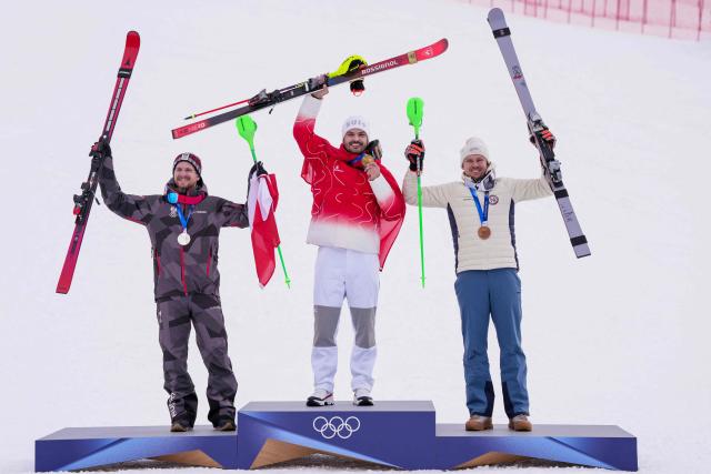 From (L-R) Austria's silver medalist Fabio Gstrein, Switzerland's gold medalist Loic Meillard, and Norway's bronze medalist Henrik Kristoffersen celebrate on the podium of the men's slalom alpine skiing event during the Milano Cortina 2026 Winter Olympic Games at the Stelvio Ski Centre in Bormio (Valtellina) on February 16, 2026. (Photo by Dimitar DILKOFF / AFP)