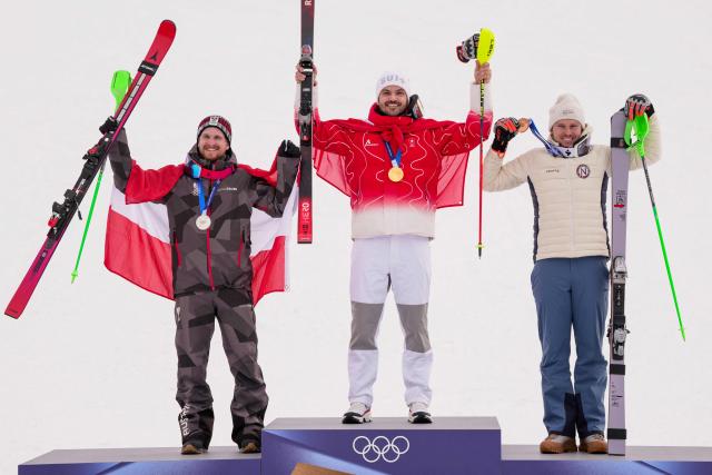 From (L-R) Austria's silver medalist Fabio Gstrein, Switzerland's gold medalist Loic Meillard, and Norway's bronze medalist Henrik Kristoffersen celebrate on the podium of the men's slalom alpine skiing event during the Milano Cortina 2026 Winter Olympic Games at the Stelvio Ski Centre in Bormio (Valtellina) on February 16, 2026. (Photo by Dimitar DILKOFF / AFP)
