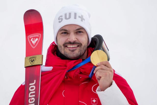 Switzerland's gold medalist Loic Meillard holds up his medal on the podium of the men's slalom alpine skiing event during the Milano Cortina 2026 Winter Olympic Games at the Stelvio Ski Centre in Bormio (Valtellina) on February 16, 2026. (Photo by Dimitar DILKOFF / AFP)
