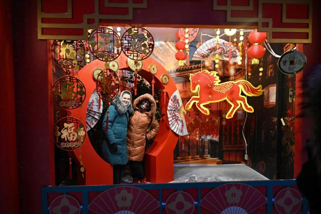 Women pose for pictures during the Lunar New Year of the Horse's eve celebrations at Moscow's Manezhnaya Square on February 16, 2026. (Photo by HECTOR RETAMAL / AFP)