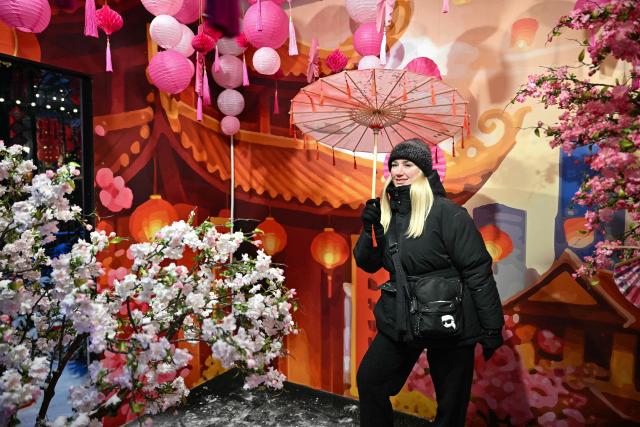 A woman poses for pictures during the Lunar New Year of the Horse's eve celebrations at Moscow's Manezhnaya Square on February 16, 2026. (Photo by HECTOR RETAMAL / AFP)