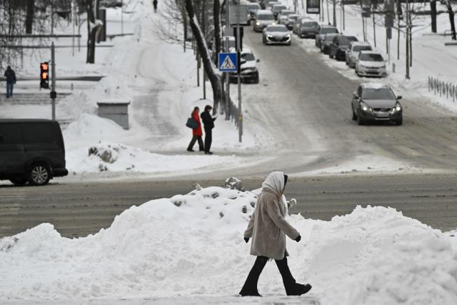 Pedestrians walk along a snow-covered road in central Kyiv following overnight snowfall on February 16, 2026, amid the Russian invasion of Ukraine. (Photo by Genya SAVILOV / AFP)