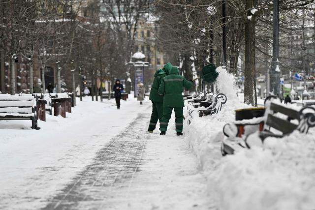 Municipal workers clear snow in central Kyiv following overnight snowfall on February 16, 2026, amid the Russian invasion of Ukraine. (Photo by Genya SAVILOV / AFP)