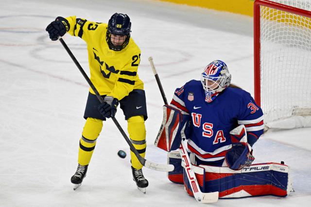 Sweden's #23 Thea Johansson (L) fights for the puck with USA's goalkeeper #31 Aerin Frankel (R) during the women's play-off semi-final ice hockey match between USA and Sweden at the Milano Santagiulia Ice Hockey Arena during the Milano Cortina 2026 Winter Olympic Games in Milan, on February 16, 2026. (Photo by Alexander NEMENOV / AFP)