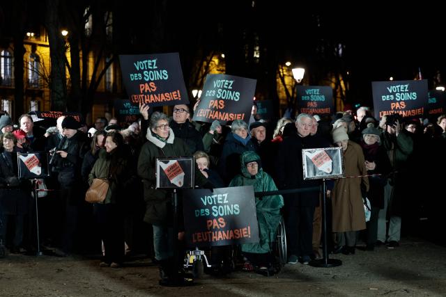 People hold placards reading "Vote for cares. Not euthanasia" during a demonstration against a bill for the creation of a right to assisted dying, at Esplanade des Invalides in Paris on February 16, 2026. (Photo by STEPHANE DE SAKUTIN / AFP)