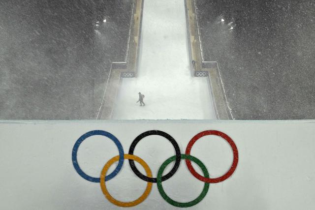 A staff member attempts to clear the course during heavy snowfall prior to the freestyle skiing women's freeski big air final run 1 during the Milano Cortina 2026 Winter Olympic Games at Livigno Snow Park, in Livigno (Valtellina), on February 16, 2026. (Photo by Jeff PACHOUD / AFP)