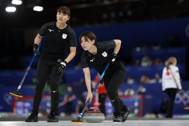 Japan's Kaho Onodera (R) and Japan's Yuna Kotani compete in the curling women's round robin between Japan and Canada during the Milano Cortina 2026 Winter Olympic Games at the Cortina Curling Olympic Stadium in Cortina d’Ampezzo on February 16, 2026. (Photo by Odd ANDERSEN / AFP)