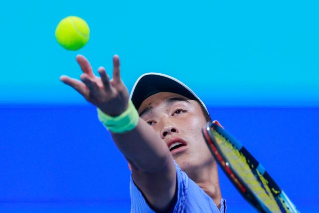 China's Shang Juncheng serves a ball against Russia’s Daniil Medvedev during their men’s singles match at the Qatar Open tennis tournament in Doha on February 16, 2026. (Photo by Karim JAAFAR / AFP)