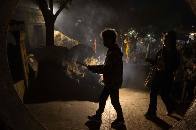 People hold incense sticks while walking around the A-Ma Temple during the start of celebrations of the Chinese Lunar New Year in Macau late February 16, 2026. (Photo by Eduardo Leal / AFP)