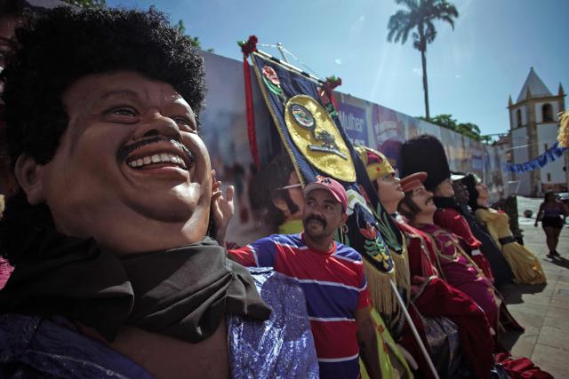 A puppeteer checks puppets before the start of the Giant Puppets parade during carnival celebrations in the city of Olinda, Pernambuco state, Brazil, on February 16, 2026. This year, Brazilian film “O Agente Secreto” (The Secret Agent) was represented with giant puppets of director Kleber Mendonca Filho and actor Wagner Moura, along with the Pitombeiras street carnival group, a street party depicted in the film. (Photo by Diego Nigro / AFP)