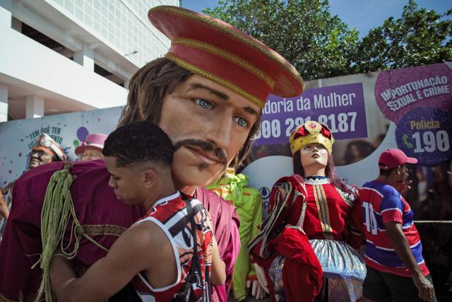 A puppeteer checks puppets before the start of the Giant Puppets parade during carnival celebrations in the city of Olinda, Pernambuco state, Brazil, on February 16, 2026. This year, Brazilian film “O Agente Secreto” (The Secret Agent) was represented with giant puppets of director Kleber Mendonca Filho and actor Wagner Moura, along with the Pitombeiras street carnival group, a street party depicted in the film. (Photo by Diego Nigro / AFP)
