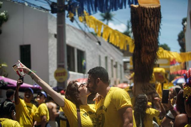 Members of the Pitombeiras street carnival group kiss during the Giant Puppets parade during carnival celebrations in the city of Olinda, Pernambuco state, Brazil, on February 16, 2026. This year, Brazilian film “O Agente Secreto” (The Secret Agent) was represented with giant puppets of director Kleber Mendonca Filho and actor Wagner Moura, along with the Pitombeiras street carnival group, a street party depicted in the film. (Photo by Diego Nigro / AFP)