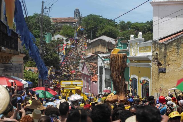 Members of the Pitombeiras street carnival group take part in the Giant Puppets parade during carnival celebrations in the city of Olinda, Pernambuco state, Brazil, on February 16, 2026. This year, Brazilian film “O Agente Secreto” (The Secret Agent) was represented with giant puppets of director Kleber Mendonca Filho and actor Wagner Moura, along with the Pitombeiras street carnival group, a street party depicted in the film. (Photo by Diego Nigro / AFP)