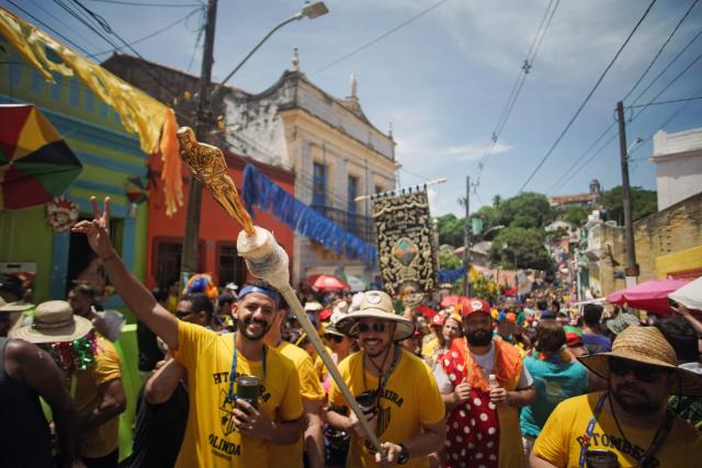 Members of the Pitombeiras street carnival group take part in the Giant Puppets parade during carnival celebrations in the city of Olinda, Pernambuco state, Brazil, on February 16, 2026. This year, Brazilian film “O Agente Secreto” (The Secret Agent) was represented with giant puppets of director Kleber Mendonca Filho and actor Wagner Moura, along with the Pitombeiras street carnival group, a street party depicted in the film. (Photo by Diego Nigro / AFP)